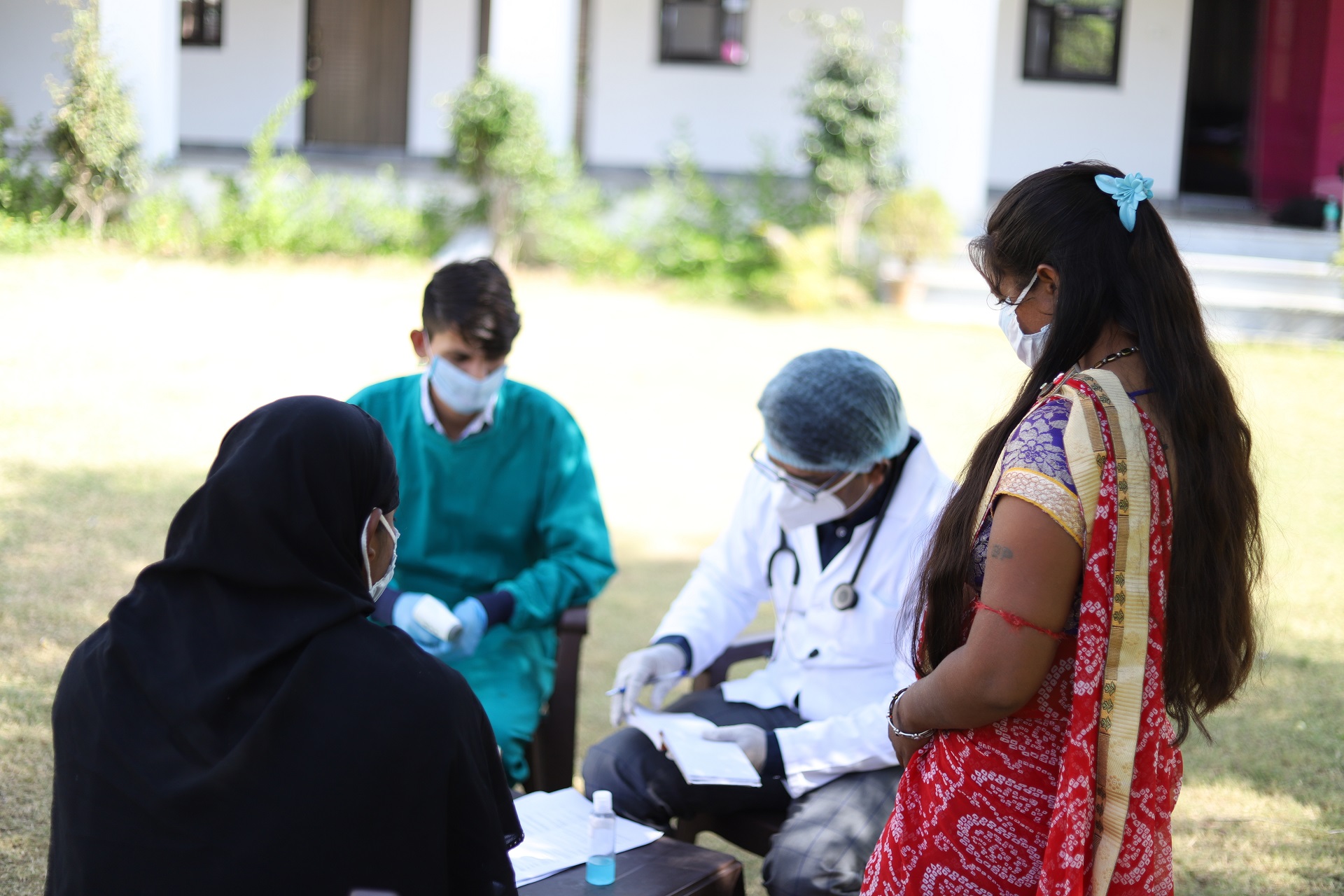 Closeup shot of doctors and patients with masks sitting on the outside and checking a list